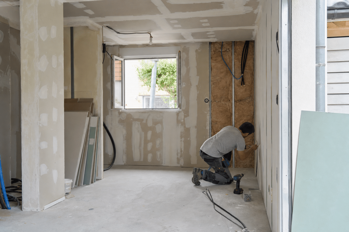 Ouvrier appliquant enduit sur cloison intérieure en rénovation